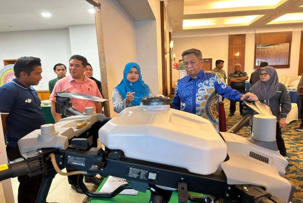 Jalaluddin(berbaju batik biru) diberikan penerangan mengenai dron untuk aktiviti pertanian selepas meramikan pada Seminar Teknologi Padi dan Seminar Pemasaran Digital Industri Asas Tani Jabatan Pertanian Negeri Sembilan Tahun 2023