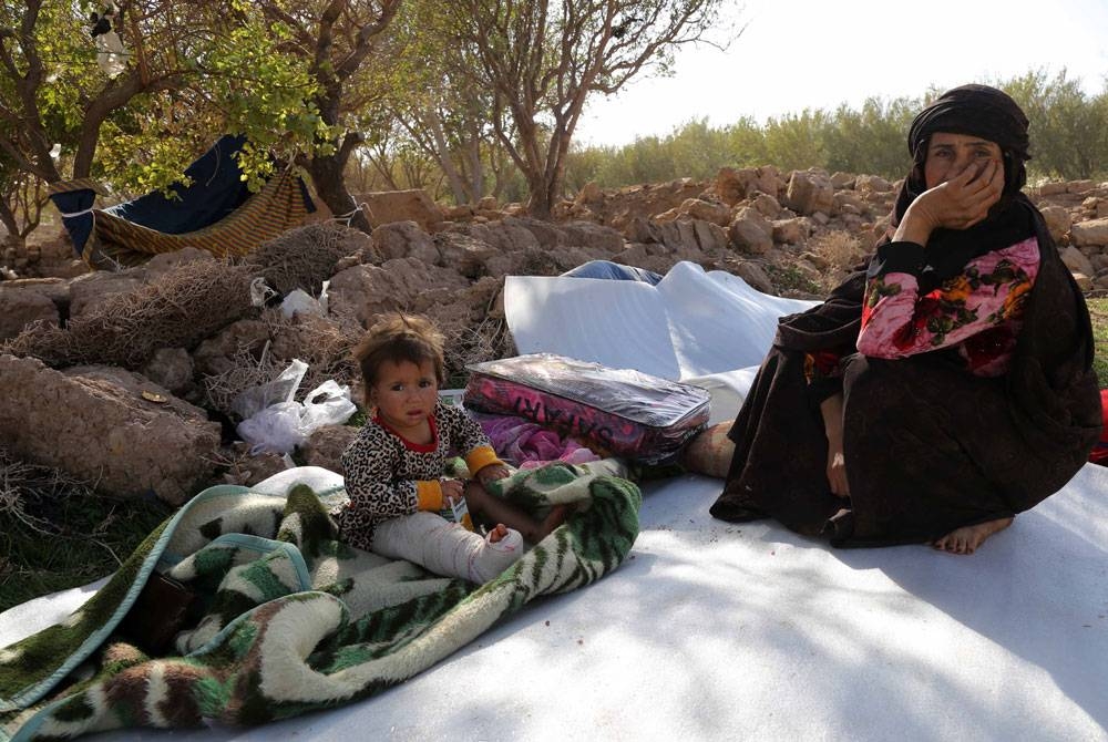 Seorang wanita dan anak kecilnya yang cedera duduk di kawasan lapang di daerah Zenda Jan, Herat yang terjejas teruk akibat gempa bumi baru-baru ini. - EPA