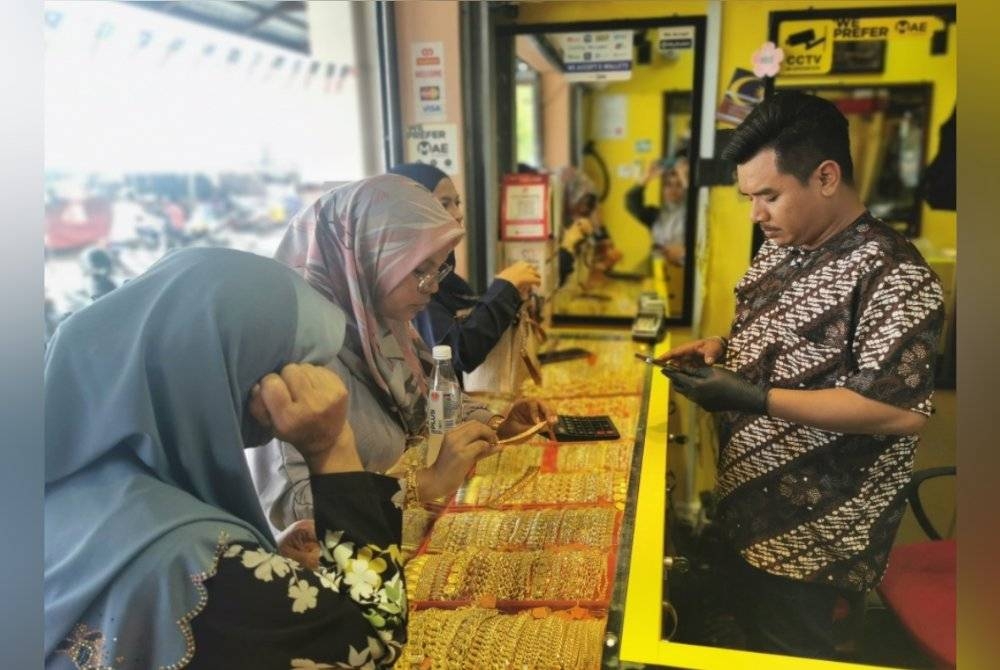 Tengku Muhamin melayan pelanggan yang datang membeli emas di kedai emasnya yang beroperasi di Pasar Payang, Kuala Terengganu.