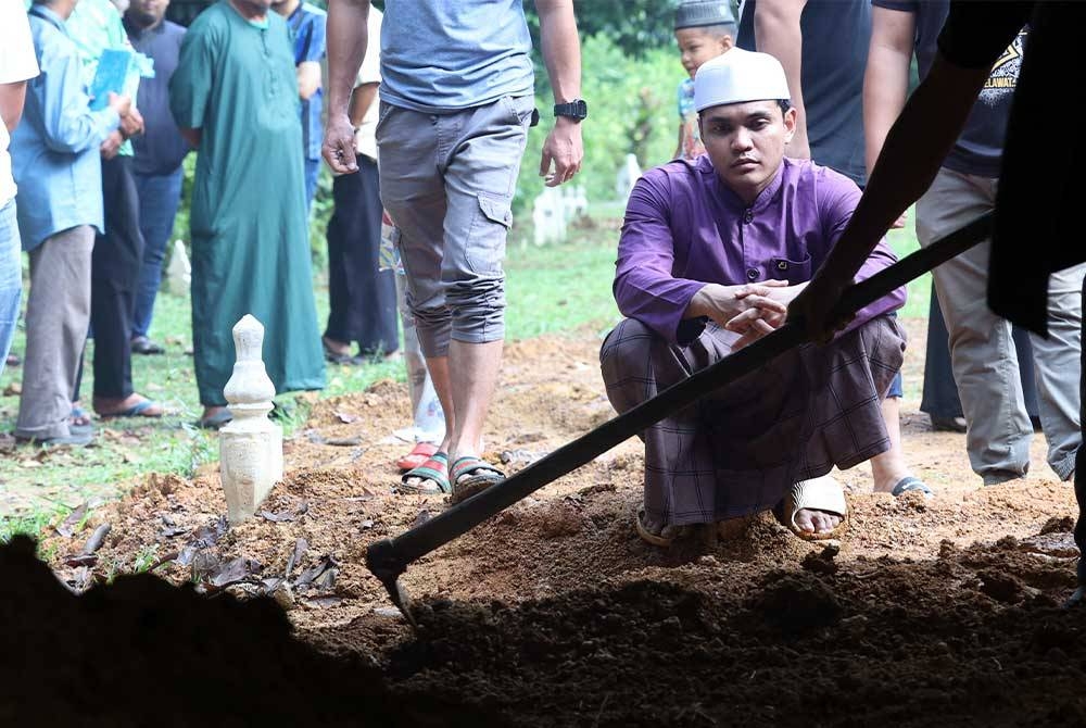 Imaduddin Md Nor, 24, anak keenam dari lapan beradik sebak ketika melihat jenazah ibunya Taibah Sulaiman, 61, dikebumikan di Tanah Perkuburan Islam Teluk Wang pada Sabtu. - Foto Bernama.