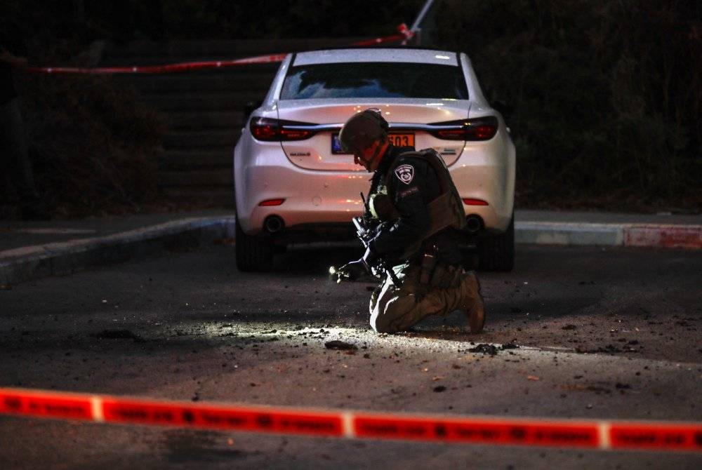 Anggota tentera Israel memeriksa lokasi di mana serpihan roket dilancarkan Hizbullah yang jatuh di bandar utara Kiryat Shmona bersempadan Lubnan. - Foto AFP