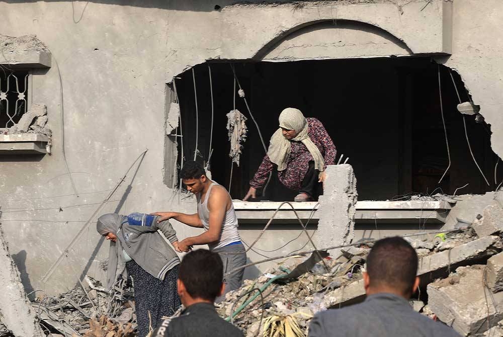 Seorang pemuda Palestin membantu untuk memindahkan penduduk dari bangunan kediaman di Rafah, selatan Genting Gaza yang musnah dibedil rejim Zionis. - Foto AFP