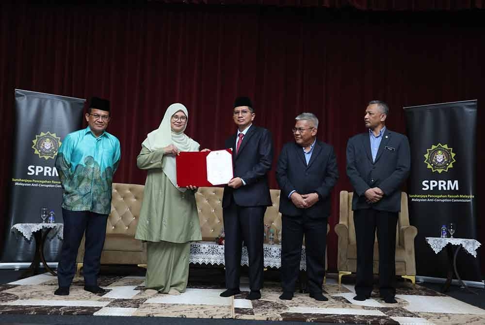 Pengerusi Masjid Zaid Harisah, Mohd Aizul (tengah) menyerahkan Ikrar Bebas Rasuah (IBR) kepada Datuk Hajah Hakimah, dengan disaksikan Datuk Seri Norazlan (kanan kedua); Pengarah SPRM Wilayah Persekutuan Kuala Lumpur, Datuk Muhamad Fauzi Husin @ Che Mamat (kanan); dan Pengarah Jawi, Datuk Mohd Ajib Ismail (kiri).