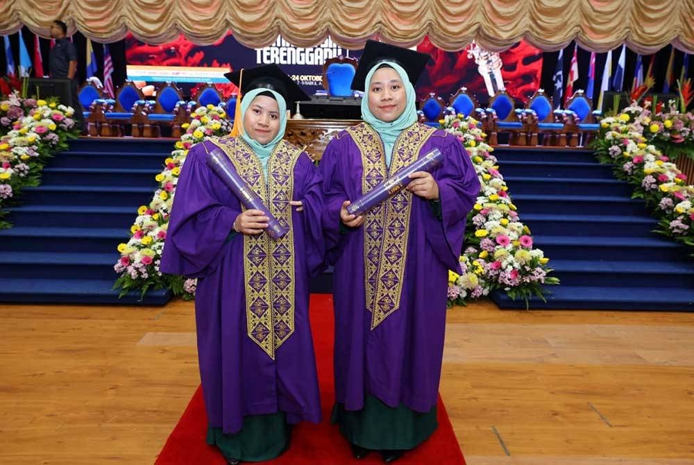 Wan Nursolehah (kiri) bersama pasangan kembarnya, Wan Nurfatihah selepas menerima skrol sempena Majlis Konvokesyen UMT Kali Ke-21 di Dewan Sultan Mizan, UMT di Kuala Nerus pada Isnin.