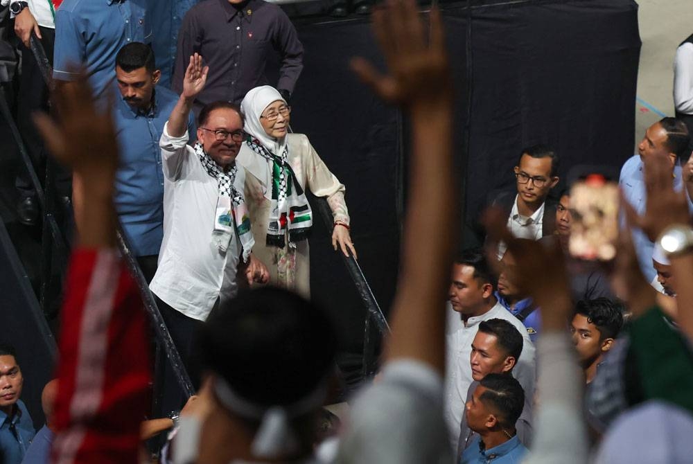 Anwar dan isteri Datuk Seri Dr Wan Azizah Wan Ismail melambaikan tangan kepada orang ramai yang hadir di Himpunan Malaysia Bersama Palestin sebelum pulang dari Stadium Axiata Arena Bukit Jalil malam ini. Foto Bernama