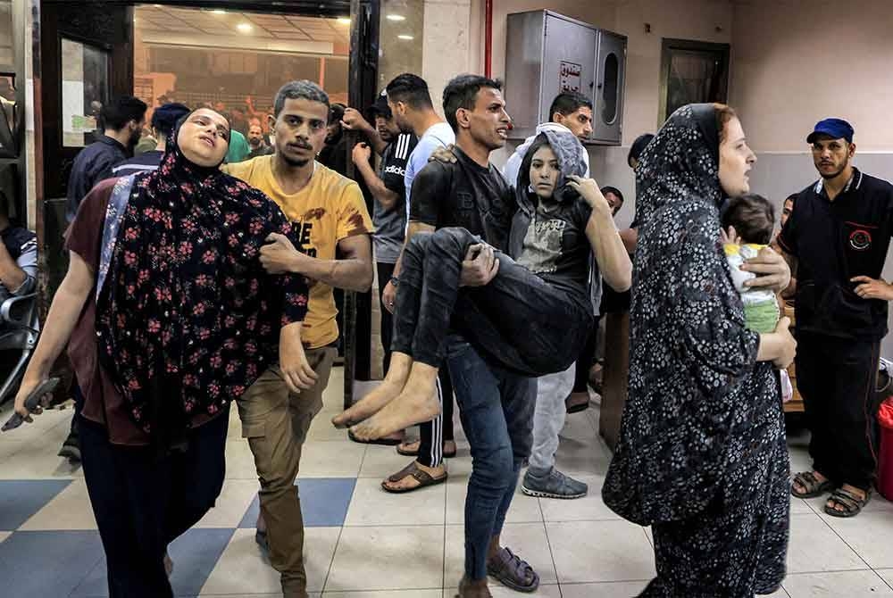 Seorang lelaki membantu seorang wanita manakala seorang lagi membawa seorang gadis ketika mereka tiba untuk rawatan selepas pengeboman Israel di Hospital Nasser di Khan Yunis di selatan Semenanjung Gaza pada Selasa. - Foto AFP