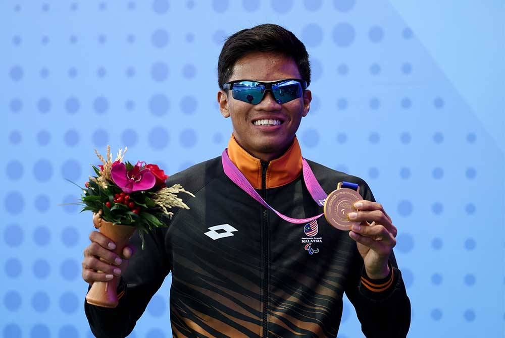 Atlet olahraga negara Muhammad Ammar Aiman menunjukkan pingat emas yang dimenanginya dalam acara akhir 400 meter lelaki T20 sempena temasya Sukan Para Asia Hangzou 2023 di Stadium Huang Long, pada Rabu. - Foto Bernama