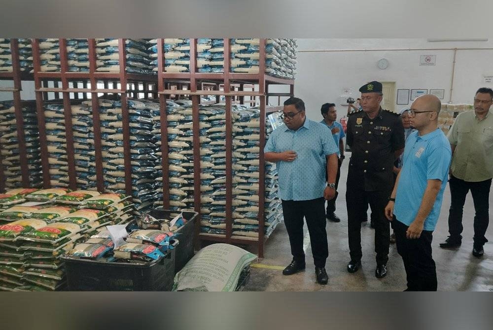 Hamizan (tengah) bersama Mohd Faris (kiri) meninjau bekalan beras yang siap untuk diedarkan di bawah Program Pelepasan Beras Putih Tempatan ke Pasaran oleh salah sebuah syarikat pembekal, Mumtaz Iman Sdn Bhd di Indera Mahkota di sini pada Khamis