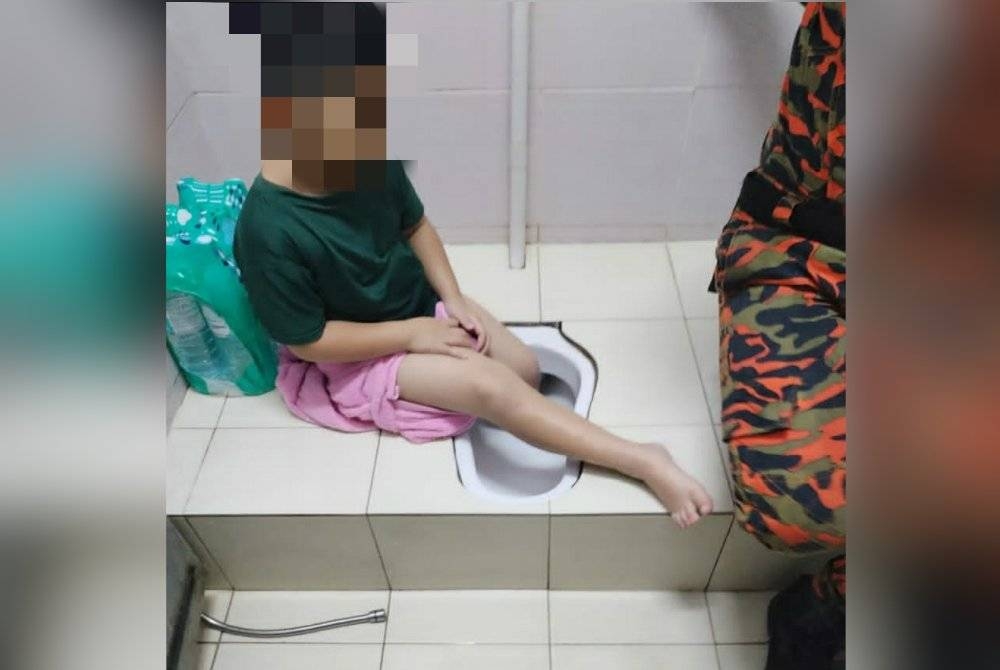 Bomba membantu mengeluarkan kaki kanak-kanak yang tersangkut dalam lubang tandas di Kampung Baru Sungai Buloh, Selangor pada Khamis.