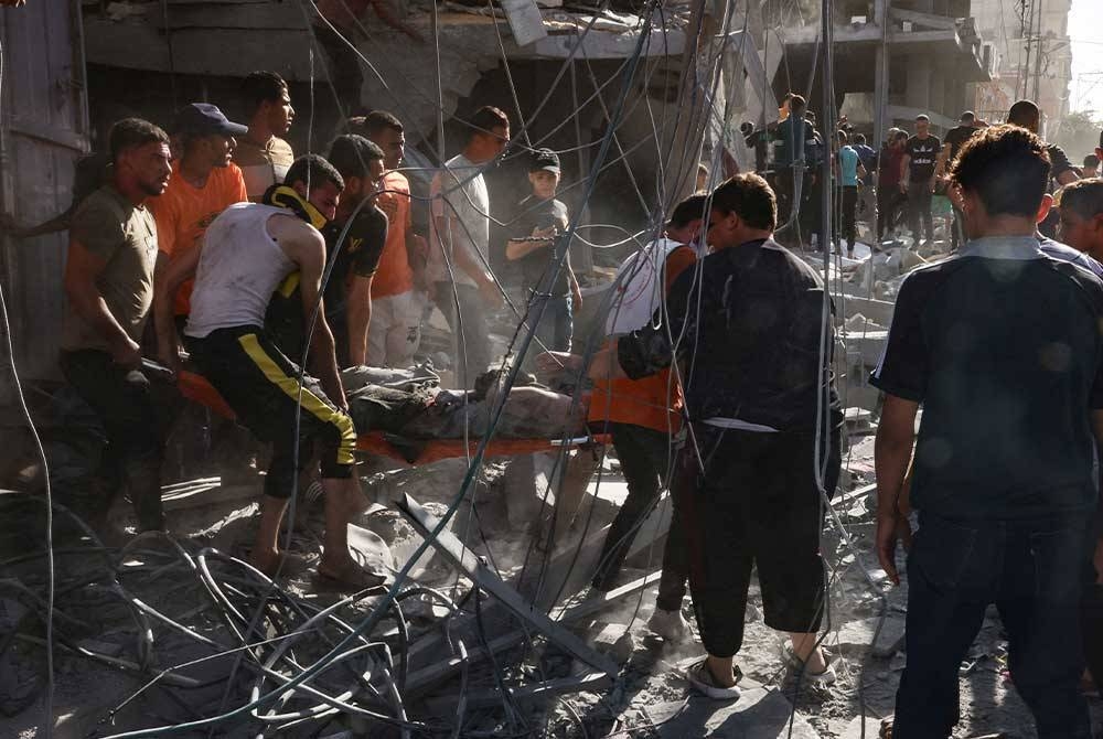 Pasukan penyelamat dan orang ramai mengangkut mayat mangsa yang terbunuh dari bawah runtuhan bangunan yang runtuh berikutan serangan udara Israel di Rafah di selatan Semenanjung Gaza pada Khamis. - Foto: AFP