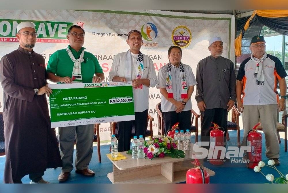 Syed Ibrahim (empat dari kanan) menyampaikan replika cek kepada wakil madrasah tahfiz disaksikan Mas Imran (tengah) pada penyerahan peralatan pencegahan kebakaran di pekarangan sebuah pasaraya di Jengka di sini, pada Jumaat.