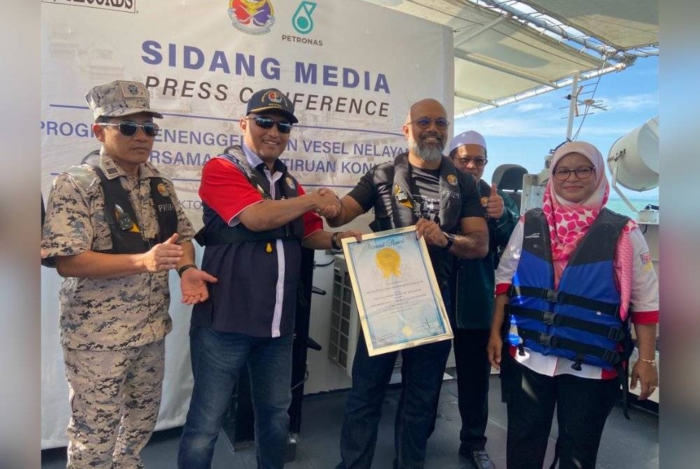 Hafiz Azzad (dua dari kanan) menyerahkan sijil Malaysia Book Of Records kepada Mohd Norzam selepas pelupusan bot nelayan asing di perairan Kuala Besar pada Jumaat.