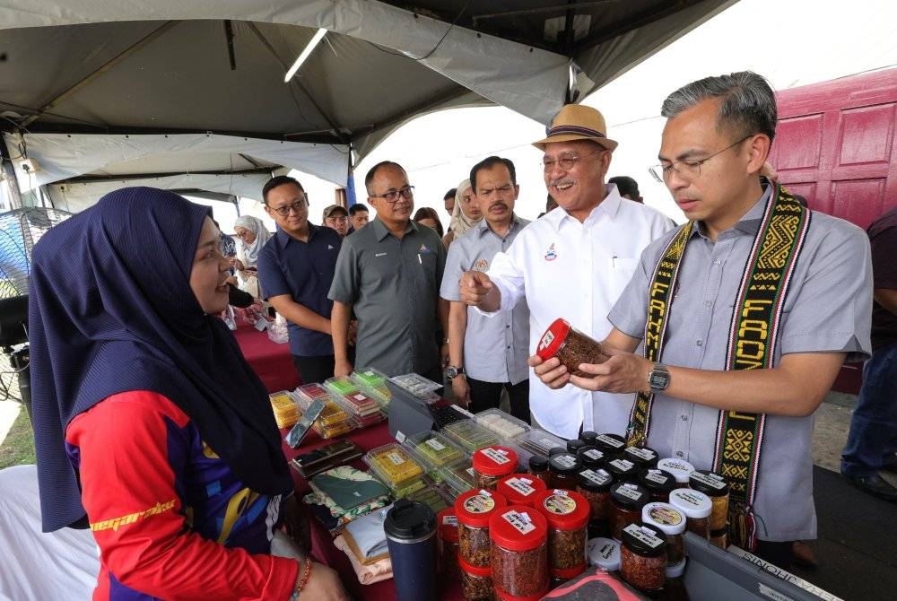 Fahmi (kanan) ketika melawat gerai jualan komuniti Kampung Lohan pada Hari Bersama Komuniti PEDi di Dewan Serbaguna Kampung Lohan hari ini. - Foto Bernama