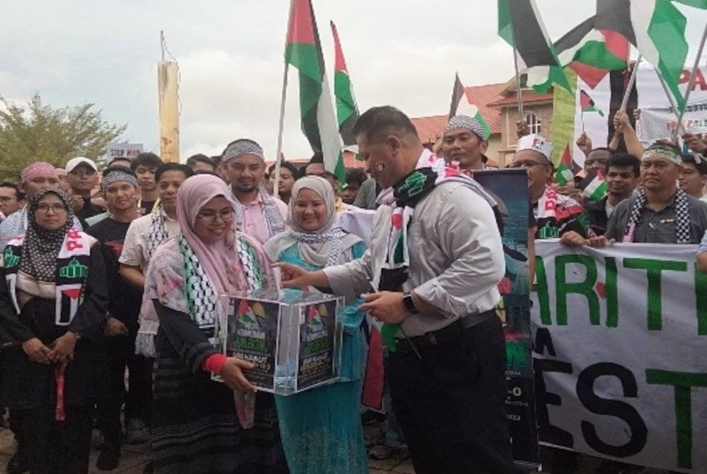 Razli (kanan) memasukkan sumbangan ke dalam tabung sebagai tanda solidariti untuk Palestin.