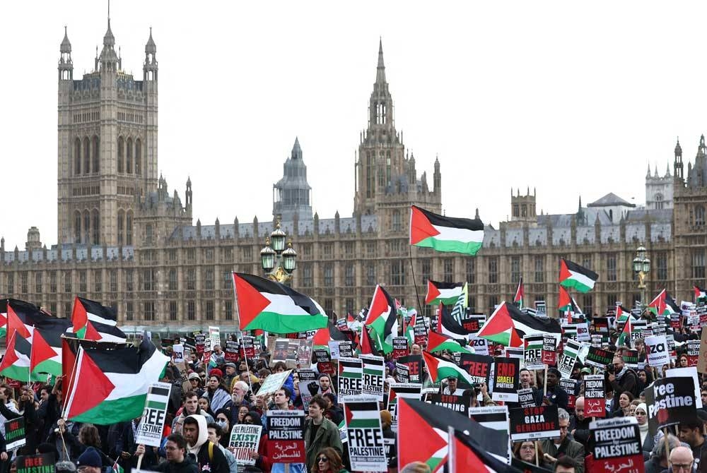 Peserta demonstrasi memegang sepanduk dan kibarkan bendera Palestin ketika March for Palestine di London pada Sabtu. - Foto AFP