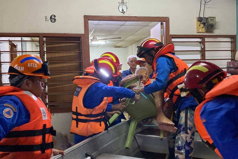 Anggota APM membantu memindahkan mangsa banjir yang terjejas di Sungai Petani pada Ahad.