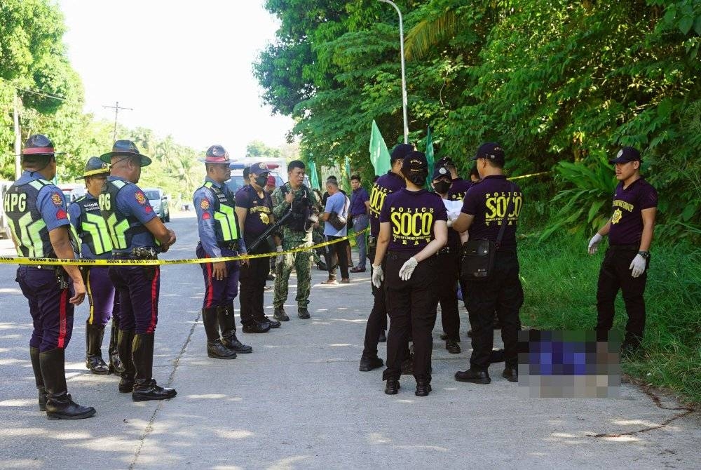 Polis mengumpul bukti di sebelah mayat di tempat kejadian tembakan di luar pusat mengundi di bandar Datu Odin Sinsuat di pulau Mindanao pada Isnin. - Foto AFP