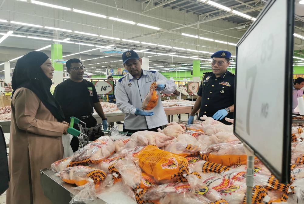 Saharuddin (dua dari kanan) meninjau harga ayam di sebuah pasar raya di Kuala Terengganu pada Rabu.