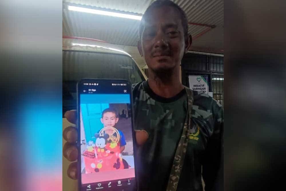 Mohd Ali menunjukkan gambar kenangan anaknya, Muhammad Aidil Adha yang lemas selepas terjatuh dalam kolam udang di Kampung Sungai Emas Hujung, Kota Kuala Muda pada Rabu.