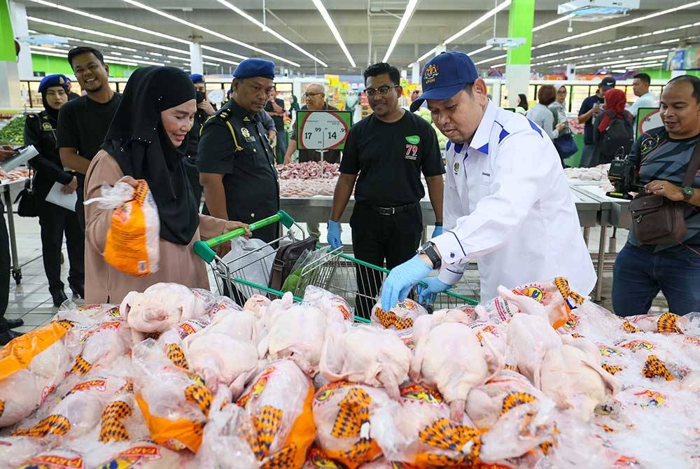 Saharuddin (kanan) memantau harga ayam segar yang dijual di sebuah pasar raya di Kuala Terengganu pada Rabu.