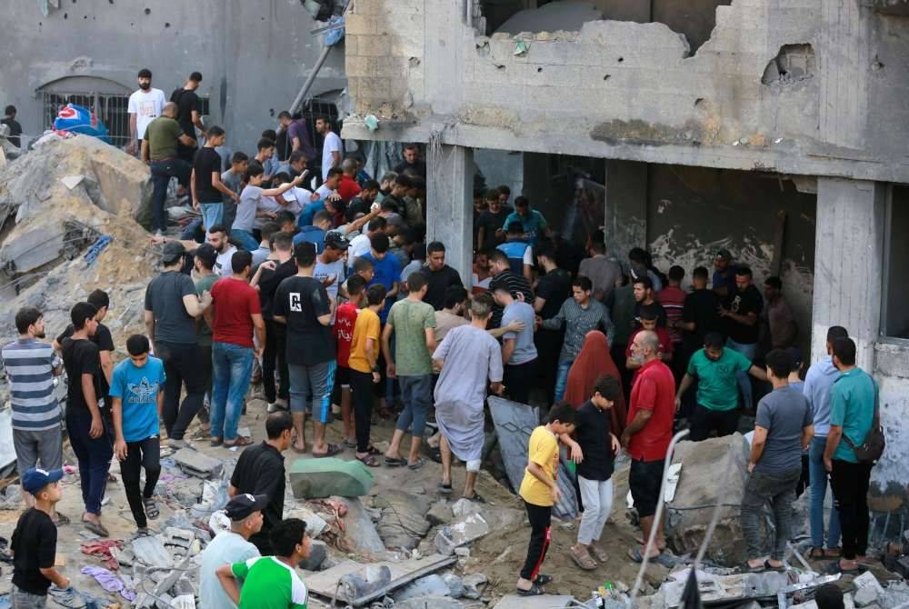 Rakyat Palestin memeriksa kemusnahan selepas serangan Israel di kem pelarian Jabalia di Semenanjung Gaza, pada Khamis. - Foto AFP