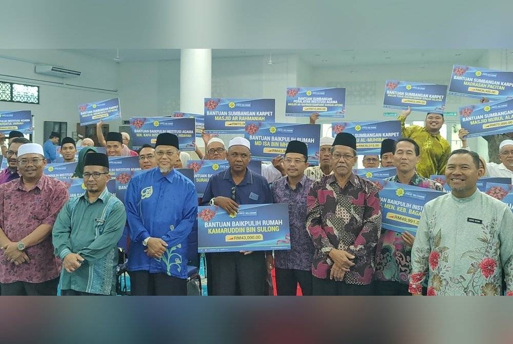 Md Yusmizan (empat dari kanan) dan bekas Mufti Selangor, Datuk Mohd Tamyes Abdul Wahid (tiga dari kiri) bergambar bersama-sama wakil agensi serta penerima pada Majlis Penyerahan Bantuan Zakat kepada Individu dan Agensi di Majis Padu Permai Sungai Besar, di sini pada Khamis.