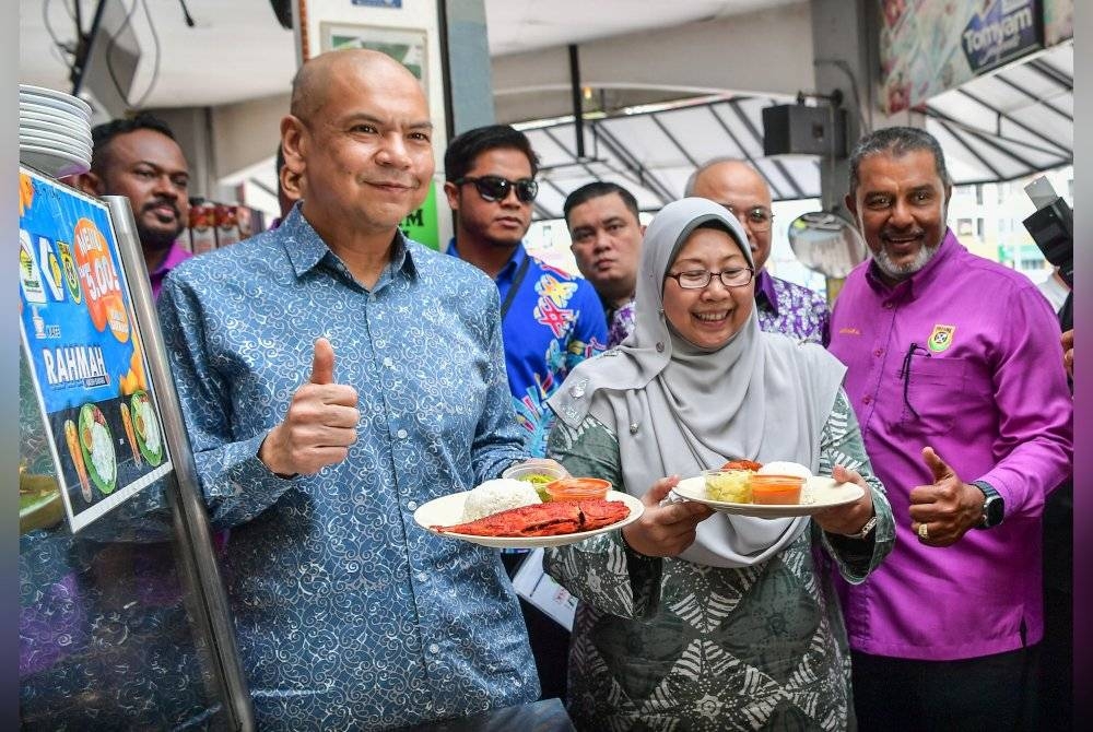 Armizan (kiri) dan Timbalan Menteri Perdagangan Dalam Negeri dan Kos Sara Hidup, Fuziah Salleh menunjukkan lauk menu Rahmah selepas sidang akhbar Kad Diskaun Khas Menu Rahmah di Restoran Ali Maju. - Foto Bernama