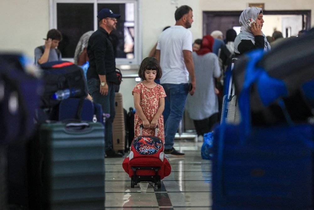 Pemegang pasport asing meninggalkan Gaza menunggu bersiap sedia untuk menyeberangi lintasan sempadan Rafah di selatan Semenanjung Gaza. - Foto AFP