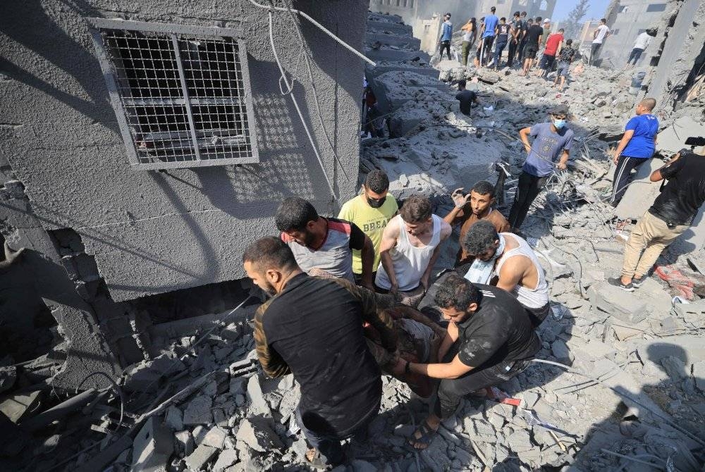 Orang ramai bertungkus-lumus membantu menyelamatkan mangsa berikutan serangan Israel ke atas kem pelarian Bureij di tengah Semenanjung Gaza. - Foto AFP