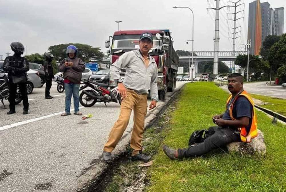 Razarudin (dua dari kanan) ketika membantu seorang penunggang motosikal yang terlibat dalam kemalangan di Lebuhraya Salak berhampiran Taman Connought pada Jumaat. - Foto Friends of PDRM