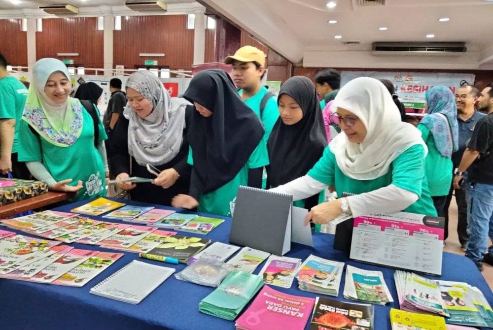 Siti Hawa (kanan) bersama peserta Program Karnival Kesihatan ReHAK di reruai jualan pelbagai buku berkaitan kesihatan pada Sabtu.