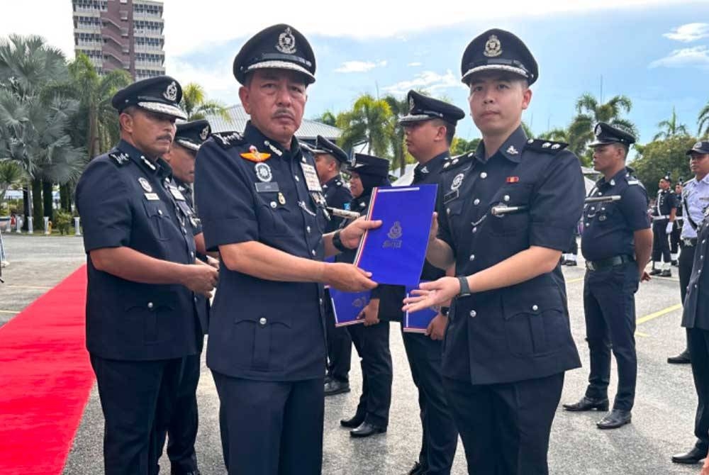 Muhamad Zaki (kiri) menyampaikan sijil penghargaan kepada Pegawai Risikan/Operasi Bahagian Siasatan Jenayah, Ibu Pejabat Polis Daerah Machang, E Soon Kiat (kanan).