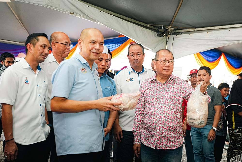 Armizan (dua dari kiri) bersama Isnin (kanan) menunjukkan ayam antara barangan yang dijual dalam PJR Beaufort di pekarangan Masjid Jamik, Kampung Kebatu Kabidang pada Ahad.