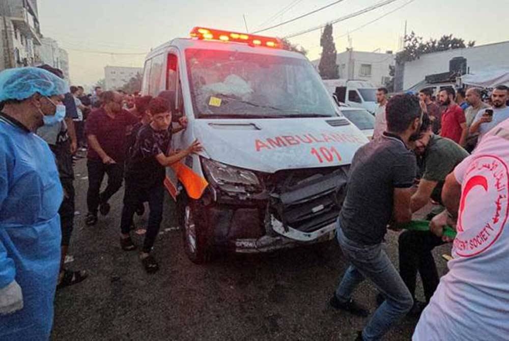 Rakyat Palestin menarik sebuah ambulans yang diserang di pintu masuk Hospital Shifa. - Foto: Reuters