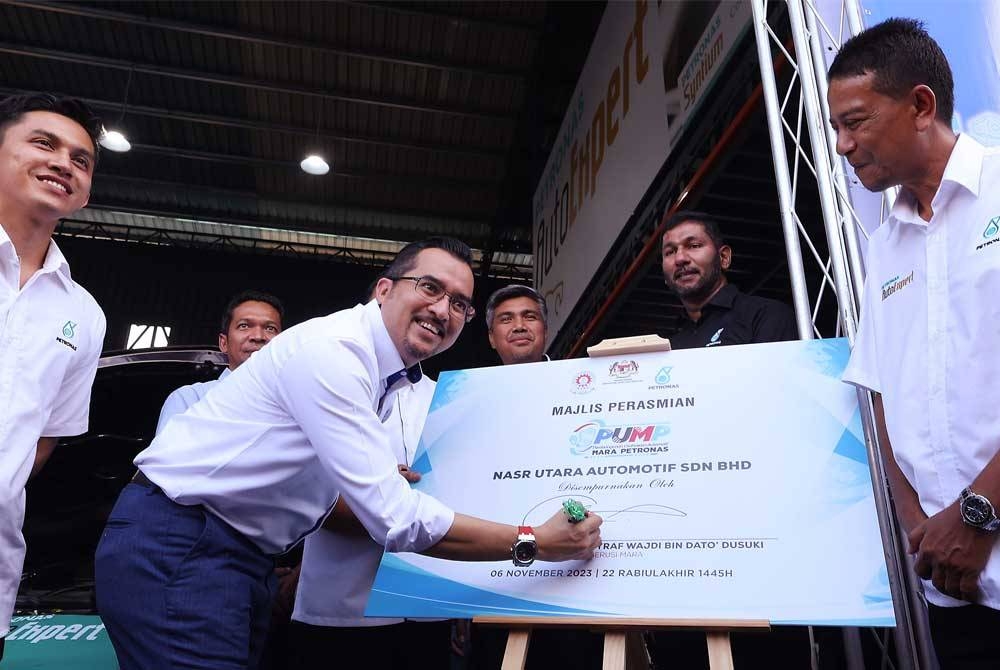 Asyraf Wajdi menandatangani plak perasmian Program Pembangunan Usahawan Automotif Mara Petronas (PUMP) di NASR Utara Automotif Sdn Bhd pada Isnin. - Foto: Bernama