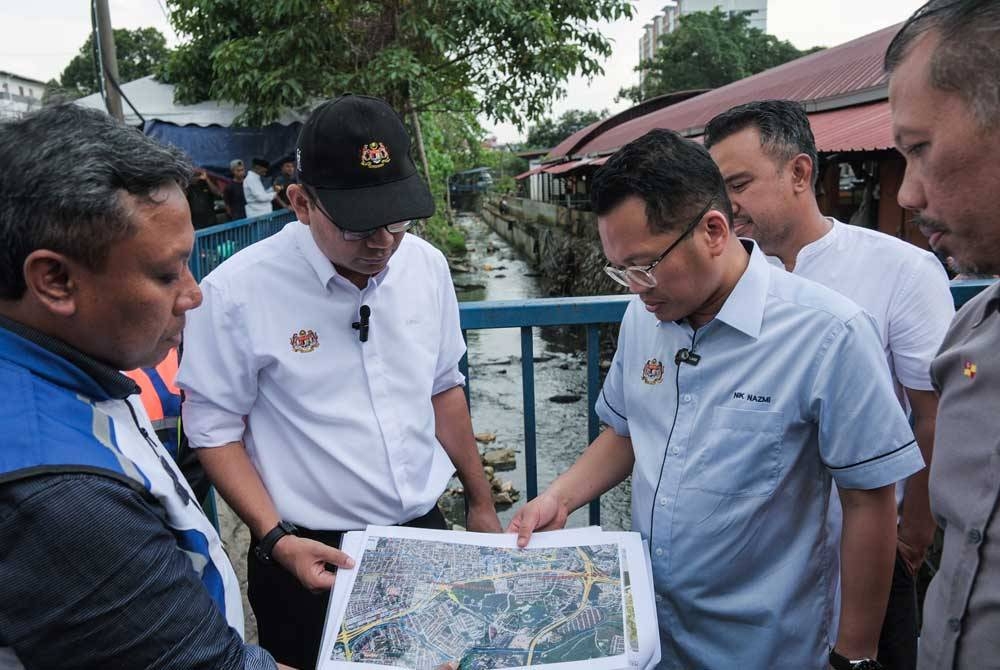 Nik Nazmi (tiga dari kiri) meneliti peta kawasan Majlis Perbandaran Selayang semasa membuat lawatan bagi meninjau isu pembuangan sampah di Pasar Borong Selayang pada Isnin. - Foto Bernama