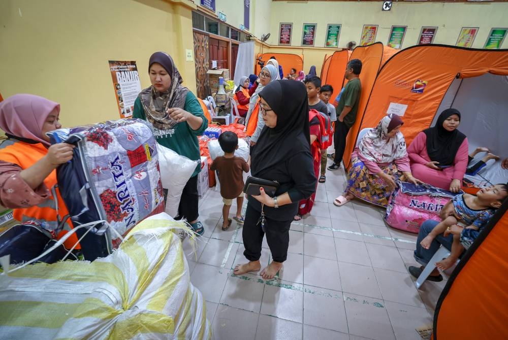 Petugas Jabatan Kebajikan Masyarakat mengagihkan barang keperluan kepada mangsa banjir di PPS Sekolah Menengah Kebangsaan Dengkil hari ini. - Foto Bernama