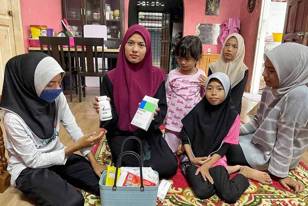 Nur Najihah (kiri) dan Fasehha menunjukkan sebahagian ubat-ubatan yang diambil anaknya bagi mengurangkan kesakitan radang buah pinggang ketika ditemui di rumahnya di Tanjung Dahan, Kuala Sungai Baru pada Selasa.