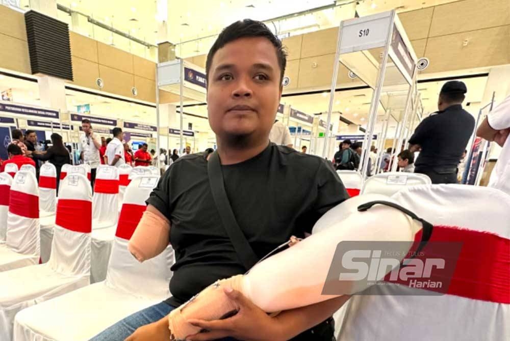 Mohamad Amiruddin memegang tangan palsu yang diterima daripada PERKESO pada Hari Bertemu Pelanggan Peringkat Negeri Kelantan di Mydin Mall Tunjong, Kota Bharu pada Rabu. - FOTO SINAR HARIAN