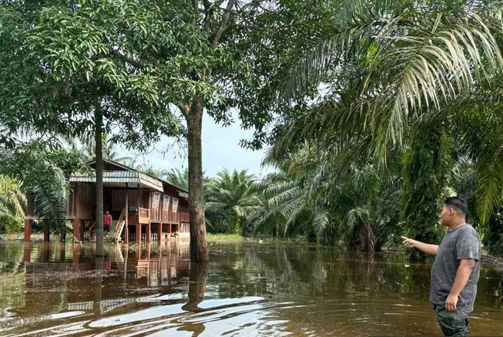 Seorang penduduk menunjukkan kawasan rumahnya yang dinaiki air. - Foto Bernama