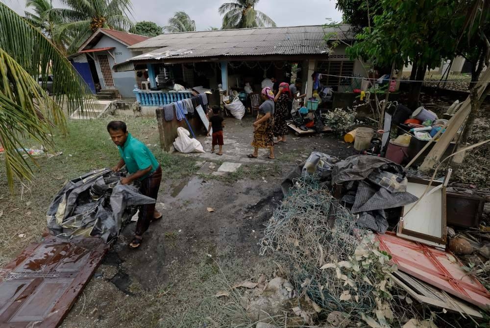 Penduduk Kampung Cemperai membersihkan rumah mereka yang dipenuhi lumpur selepas dilanda banjir. - Foto Bernama