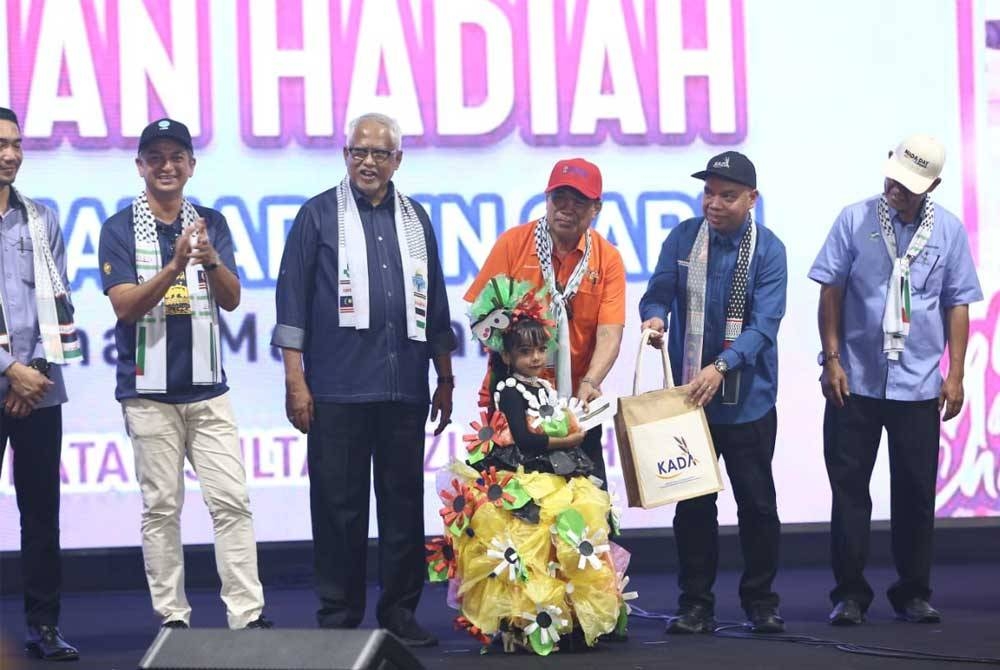 Mohamad menyampaikan hadiah kepada juara pertandingan pakaian beragam.