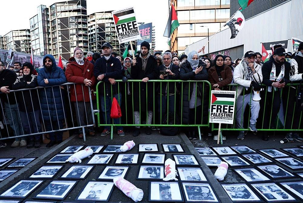 Penunjuk perasaan memegang sepanduk dan bendera di sekeliling tugu peringatan sementara dengan gambar mangsa pengeboman di Gaza, semasa &#039;Perarakan Kebangsaan Untuk Palestin&#039; di tengah London pada Sabtu. - Foto: AFP