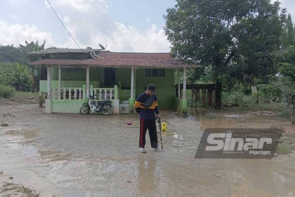 Seorang penduduk membersihkan pekarangan rumahnya di Kampung Sentosa Damai, Pasir Gudang pada Isnin akibat banjir kilat.