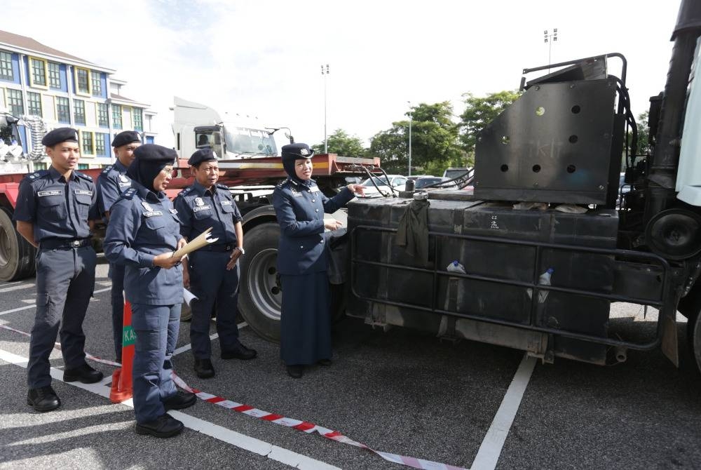 Nor Izah (kanan) menunjukkan tangki satu daripada empat treler yang ditahan JKDM Kedah di Bukit Kayu Hitam pada 7 November.