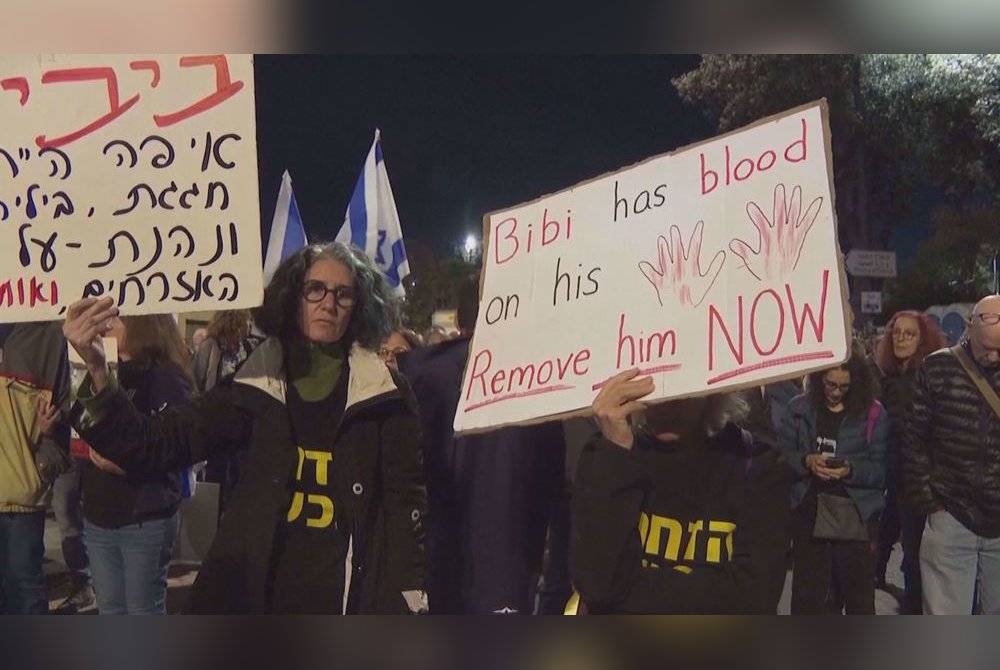 Peserta protes yang membawa plakad turut melaungkan slogan mengutuk Netanyahu. - Foto Agensi