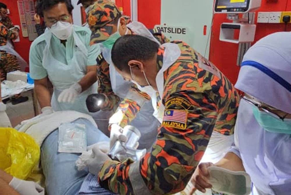 Anggota bomba berusaha mengeluarkan tangan mangsa yang tersepit dalam mesin pengisar daging ketika dirawat di Jabatan Kecemasan dan Trauma Hospital Kemaman. Foto: JBPM