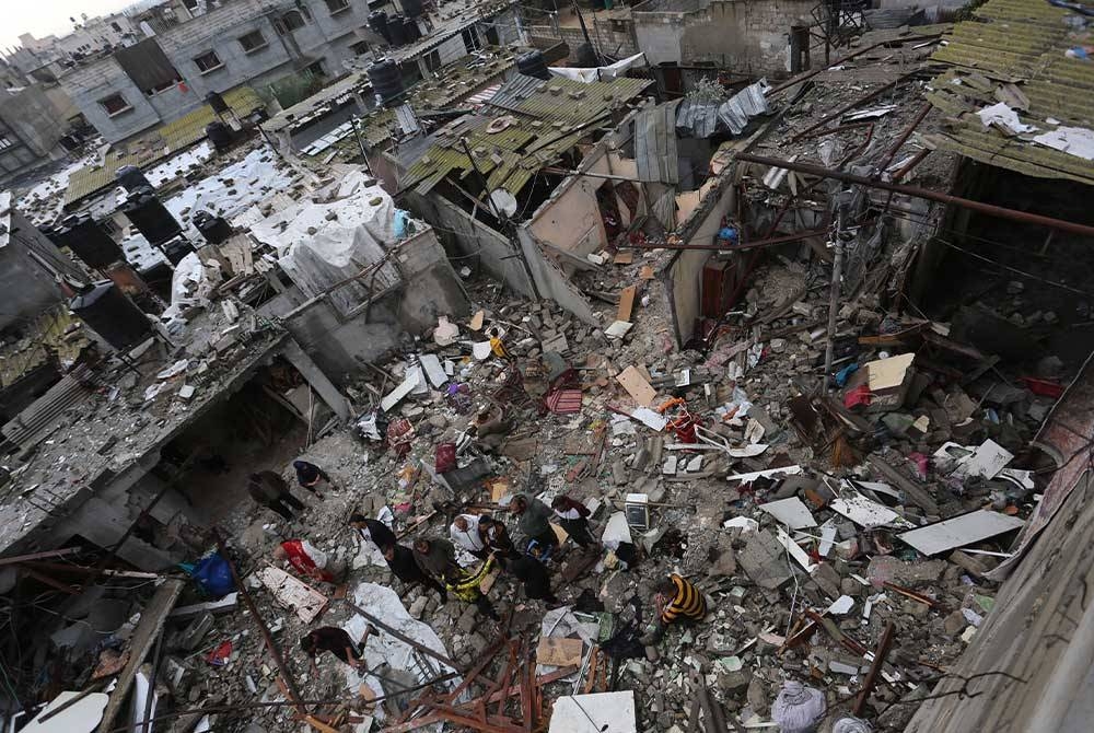 Orang ramai kelihatan di antara runtuhan bangunan yang musnah dalam serangan udara Israel di bandar Rafah, selatan Semenanjung Gaza. Foto Xinhua