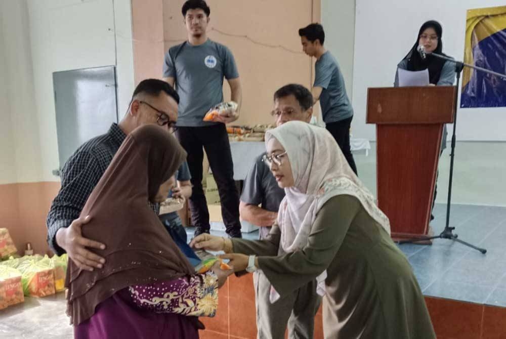 Norhaslinda (kanan) menyampaikan sumbangan berupa barangan keperluan kepada penerima sempena Program CSR DPMP di Dewan Serbaguna Kampung Padang Tembak, Teluk Muroh di sini pada Sabtu.