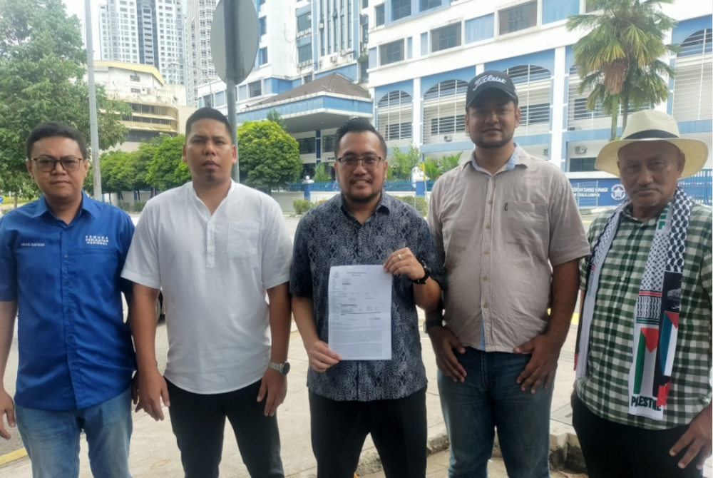 Muhammad Faiz (tengah) menunjukkan laporan polis yang dibuat Armada Bersatu berhubung video tular dikaitkan dengan Mohammad Agus di IPD Dang Wangi, Kuala Lumpur pada Sabtu.